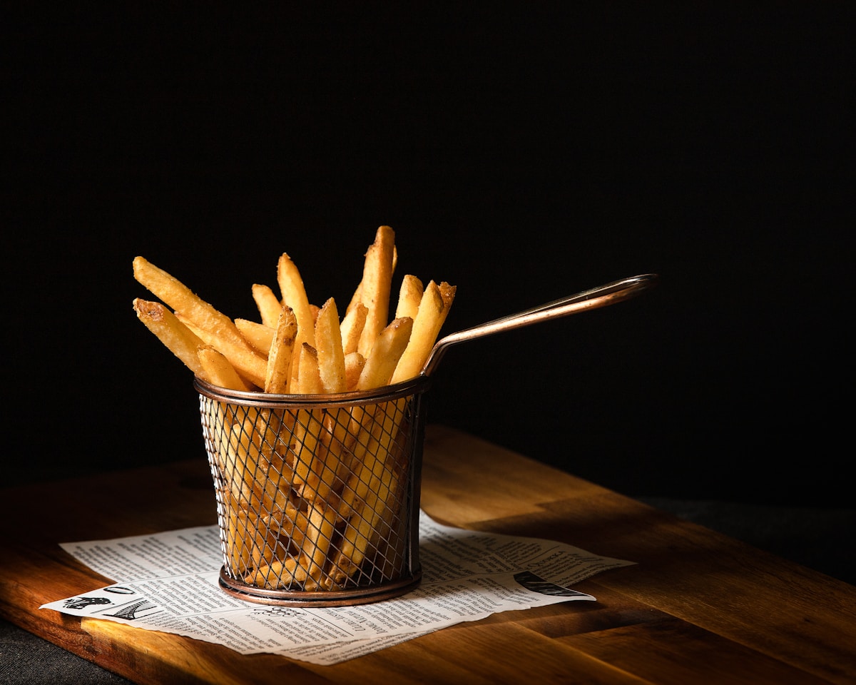 Klassische, hausgemachte Pommes frites in einem schwarzen Korb.